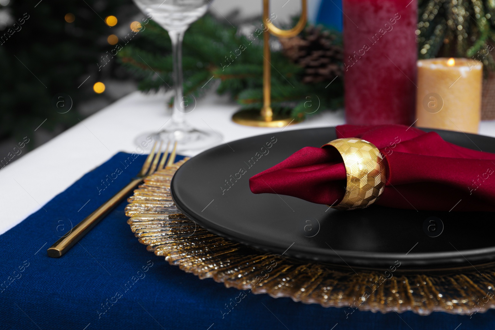 Photo of Festive place setting with beautiful dishware, cutlery and fabric napkin for Christmas dinner on white table, closeup
