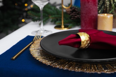 Festive place setting with beautiful dishware, cutlery and fabric napkin for Christmas dinner on white table, closeup