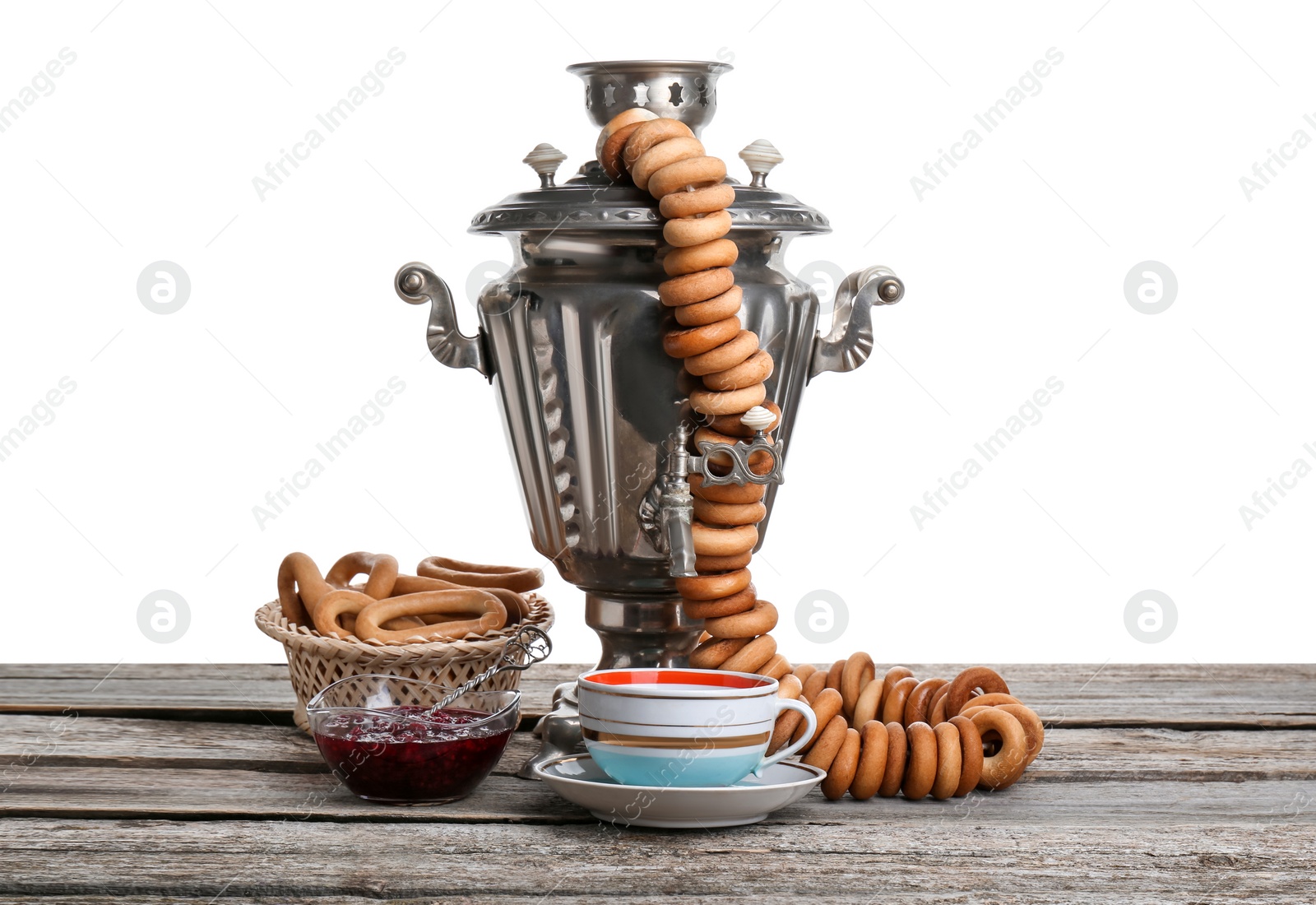 Photo of Samovar with hot tea, jam and delicious ring shaped Sushki (dry bagels) on table against white background