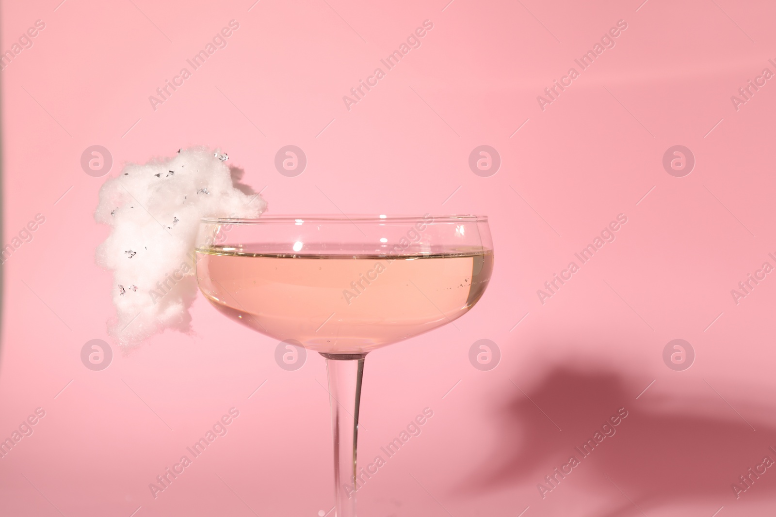 Photo of Tasty cocktail in glass decorated with cotton candy on pink background, closeup