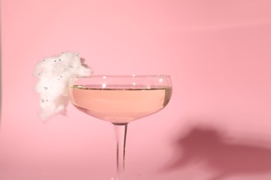 Tasty cocktail in glass decorated with cotton candy on pink background, closeup