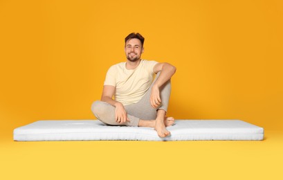Photo of Man sitting on soft mattress against orange background