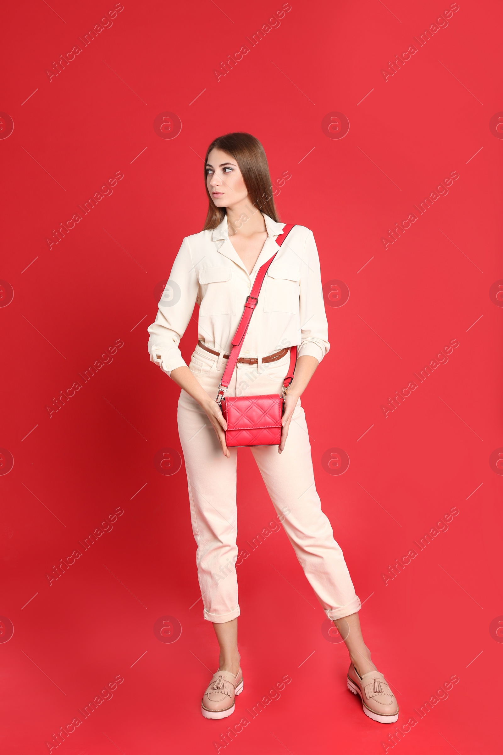 Photo of Beautiful young woman in casual outfit with stylish bag on red background