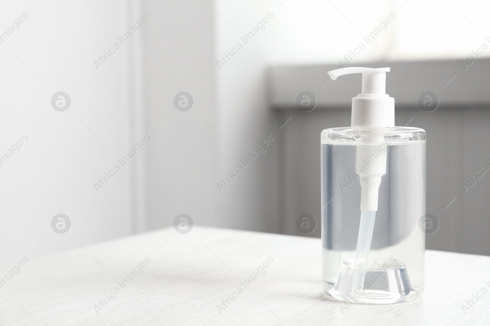 Photo of Dispenser bottle with antiseptic gel on table indoors. Space for text