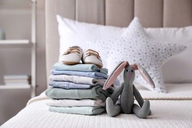 Photo of Stack of baby boy's clothes, toy and shoes on bed at home