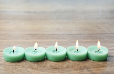 Burning turquoise decorative candles on wooden table