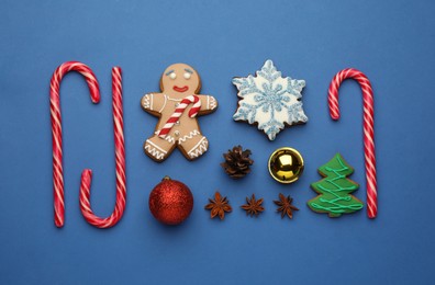 Flat lay composition with sweet candy canes and Christmas decor on blue background