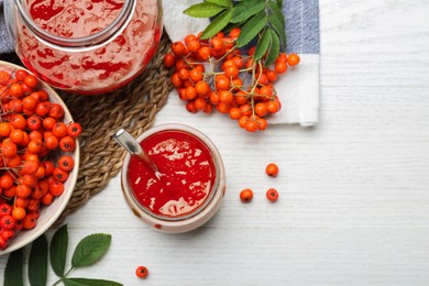 Flat lay composition with delicious rowan jam on white wooden table. Space for text