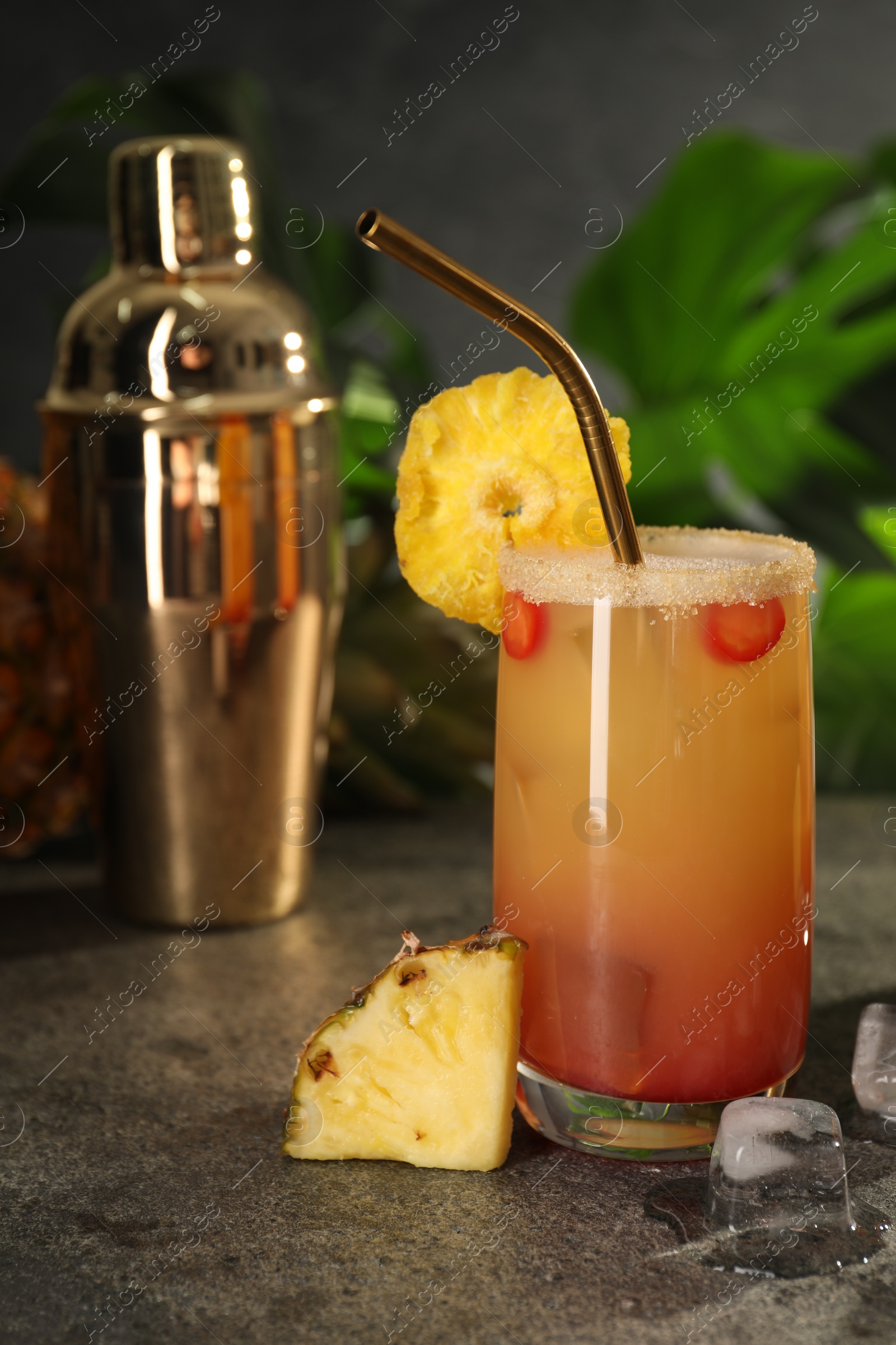 Photo of Glasses of tasty pineapple cocktail, sliced fruit and ice cubes on grey table