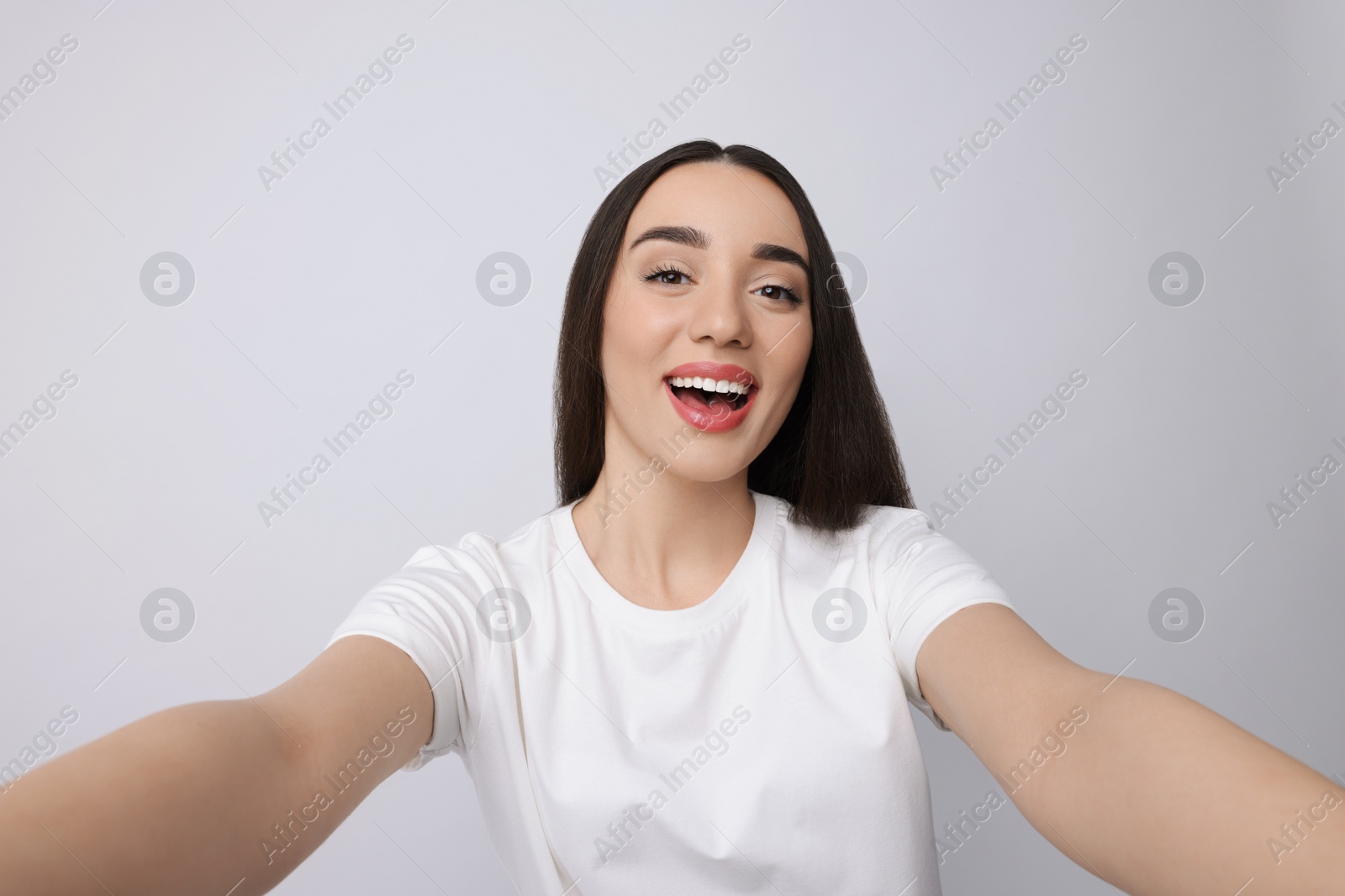 Photo of Smiling young woman taking selfie on white background