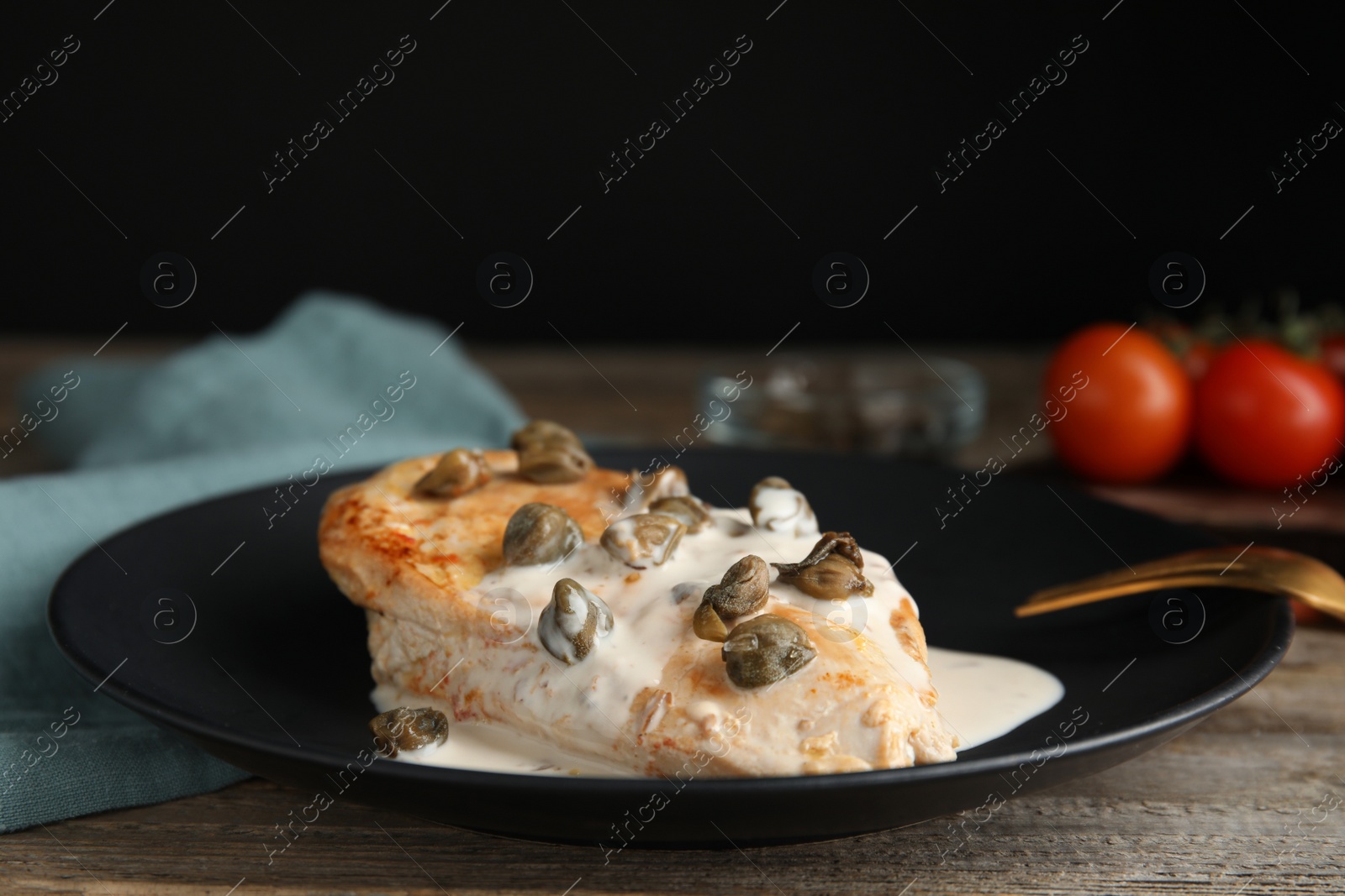 Photo of Delicious chicken fillet with capers and sauce served on wooden table, closeup