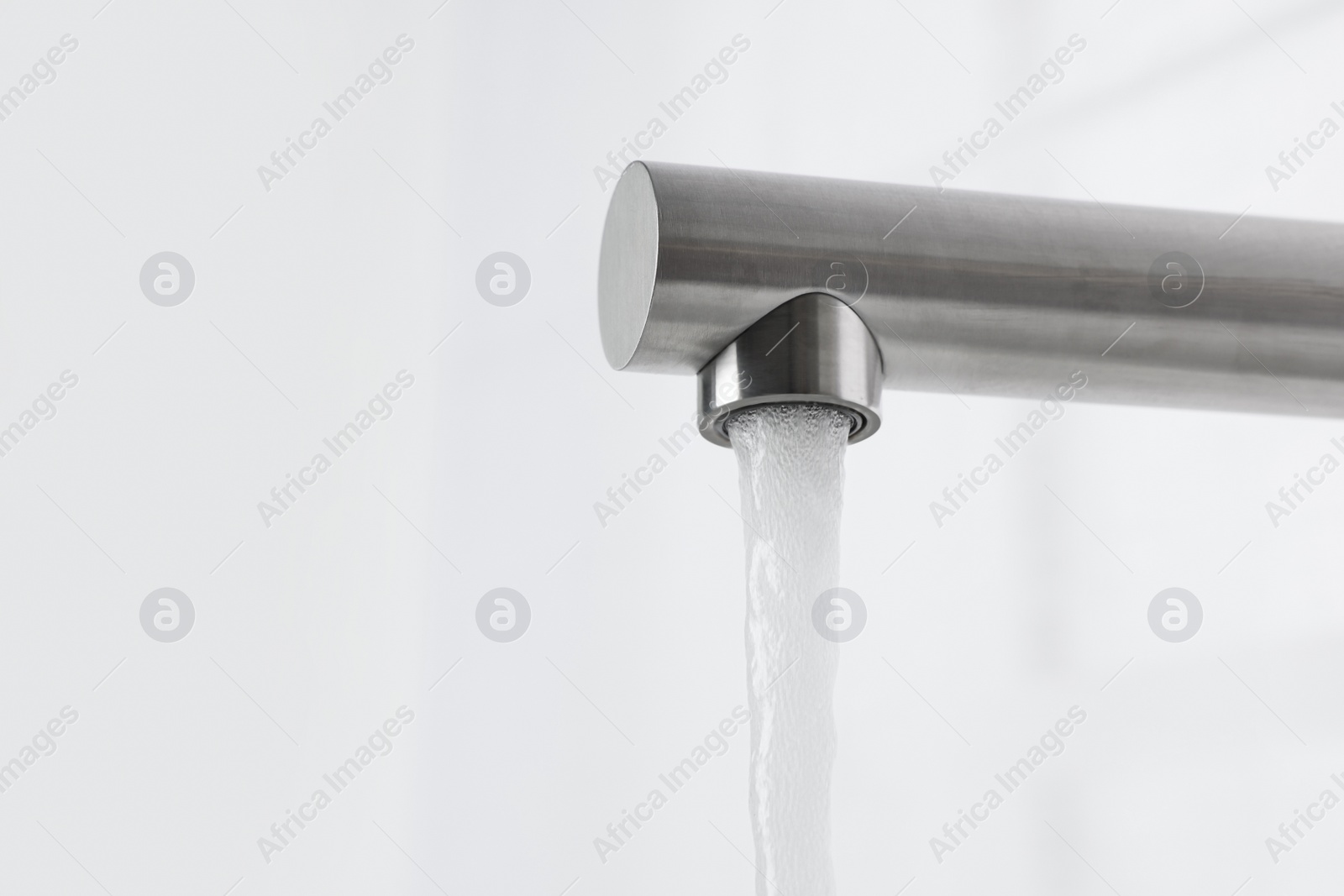 Photo of Stream of water flowing from tap on white background, closeup. Space for text