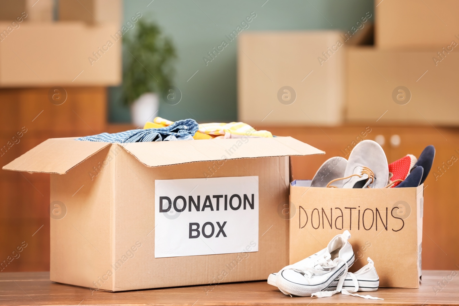 Photo of Donation boxes with clothes and shoes on table indoors