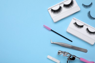 Flat lay composition with fake eyelashes on light blue background, space for text