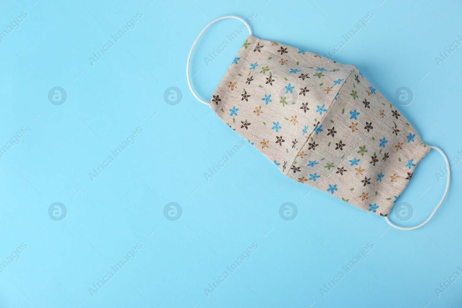 Photo of Homemade protective face mask on light blue background, top view. Space for text