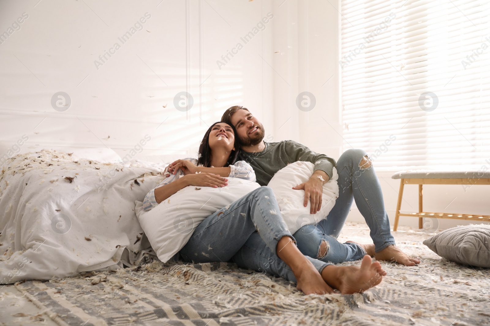 Photo of Happy young couple resting after fun pillow fight in bedroom