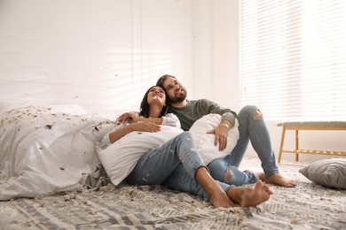 Happy young couple resting after fun pillow fight in bedroom