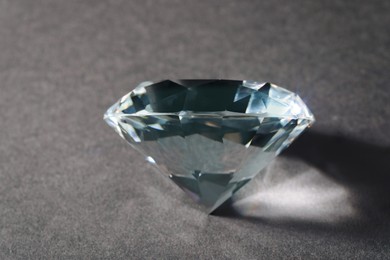Photo of Beautiful dazzling diamond on black textured background, closeup