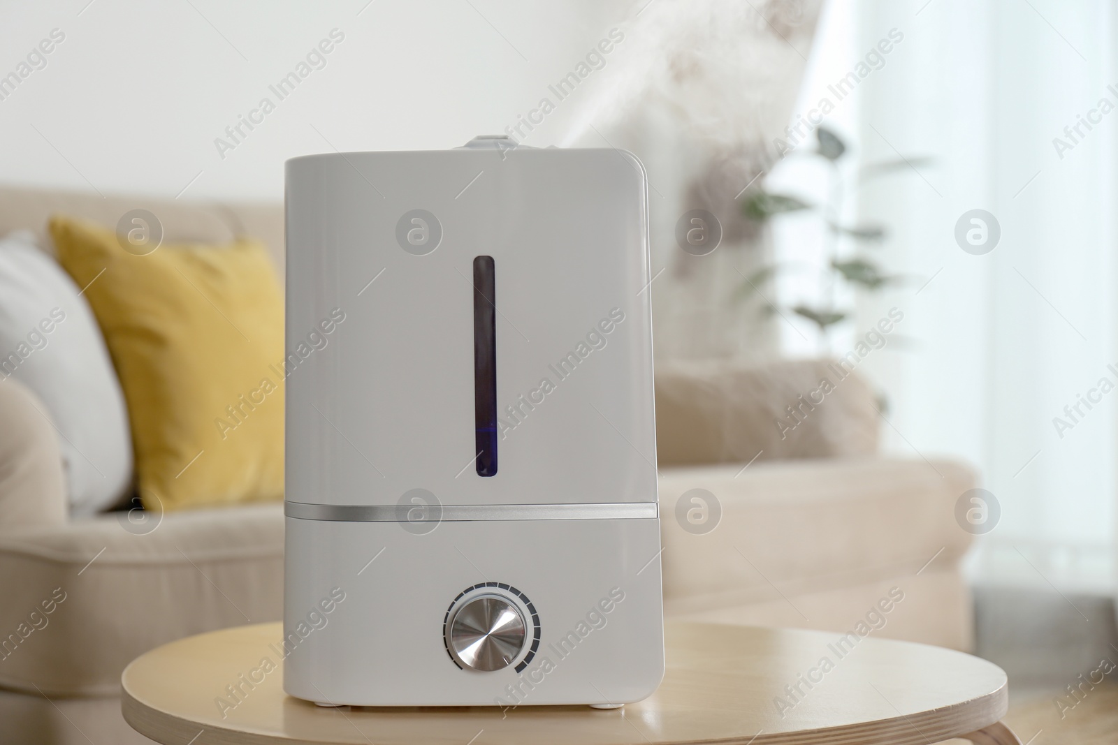 Photo of Modern air humidifier on wooden table indoors. Space for text