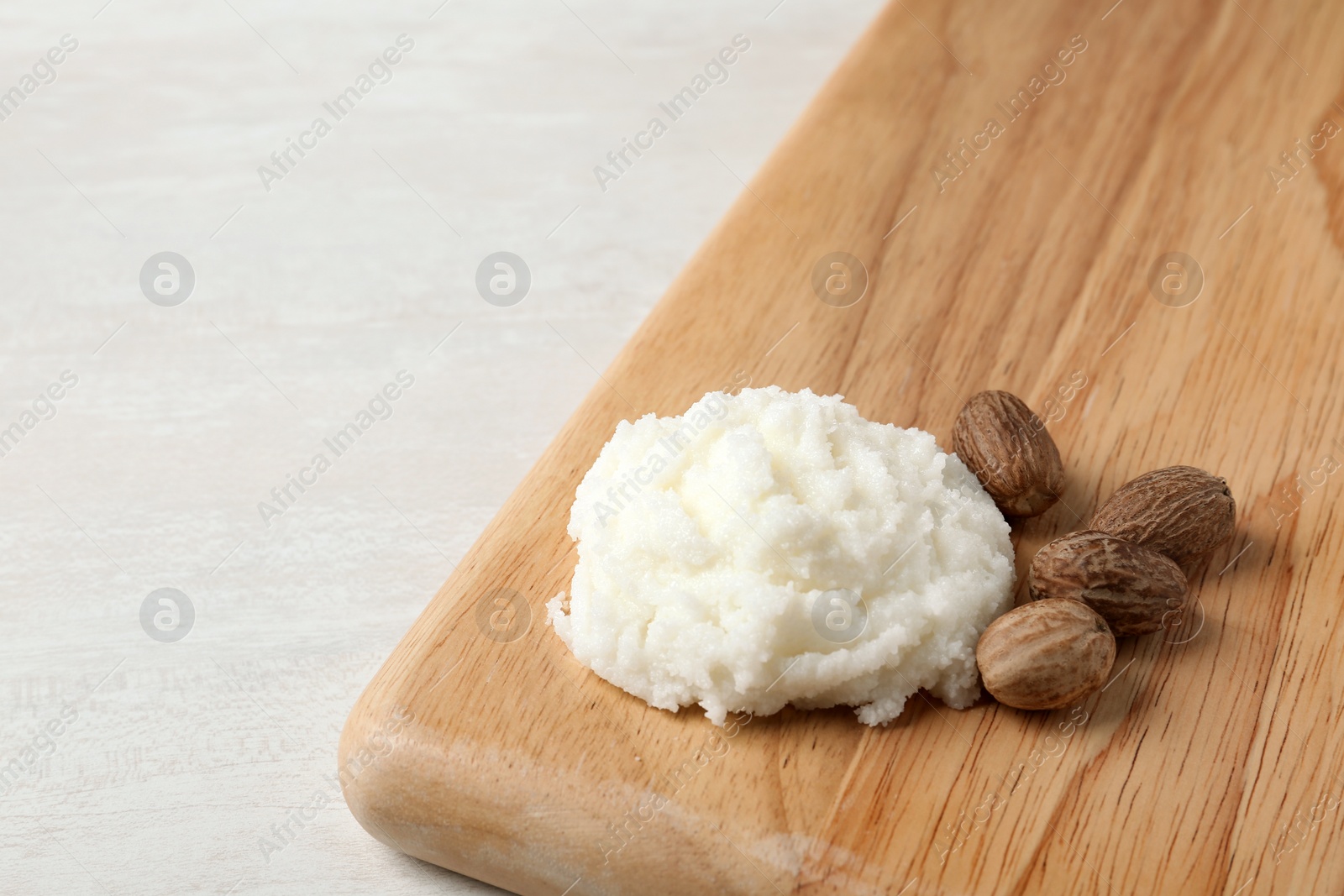 Photo of Shea butter and nuts on wooden board. Space for text