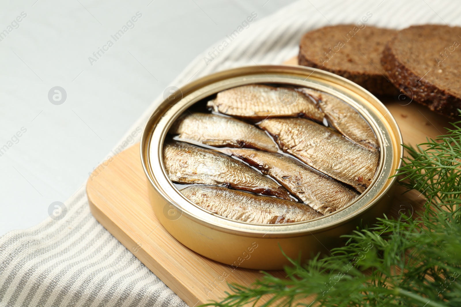 Photo of Canned sprats, dill and bread on light table, closeup. Space for text