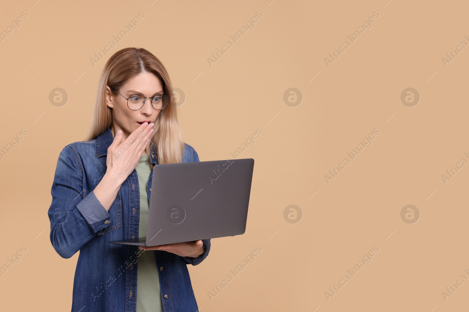 Photo of Emotional woman with laptop on beige background. Space for text