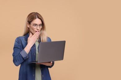 Emotional woman with laptop on beige background. Space for text