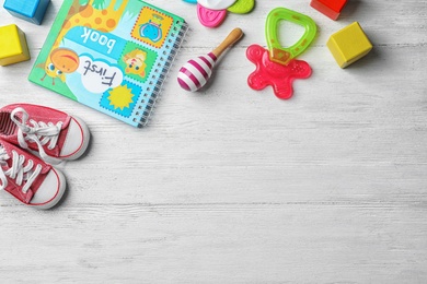 Photo of Flat lay composition with baby accessories and toys on light wooden background. Space for text