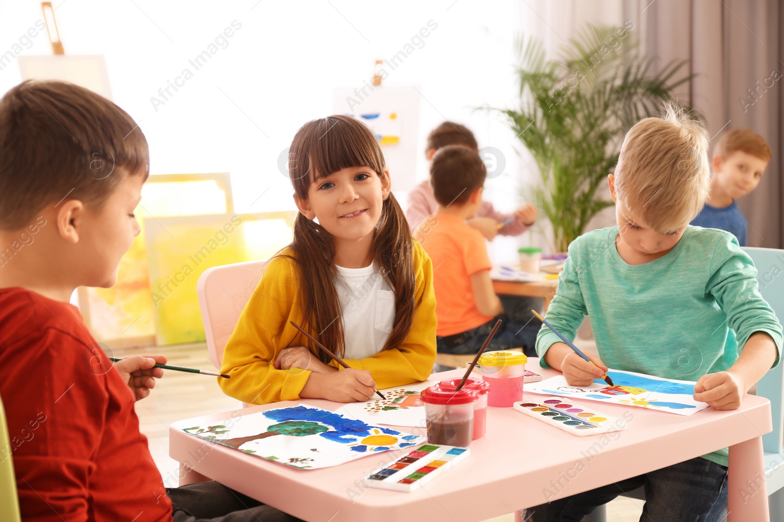 Photo of Cute little children painting at table in room