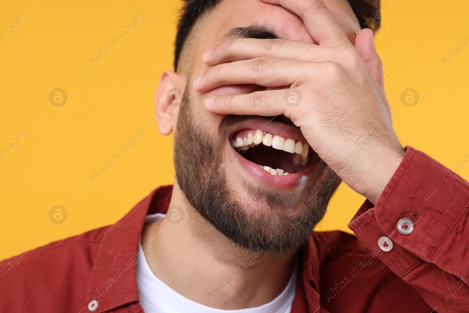 Photo of Young man laughing on yellow background, closeup