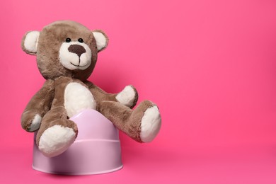 Photo of Teddy bear on baby potty against pink background, space for text. Toilet training