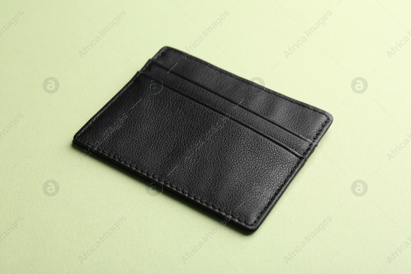Photo of Empty leather card holder on light green background
