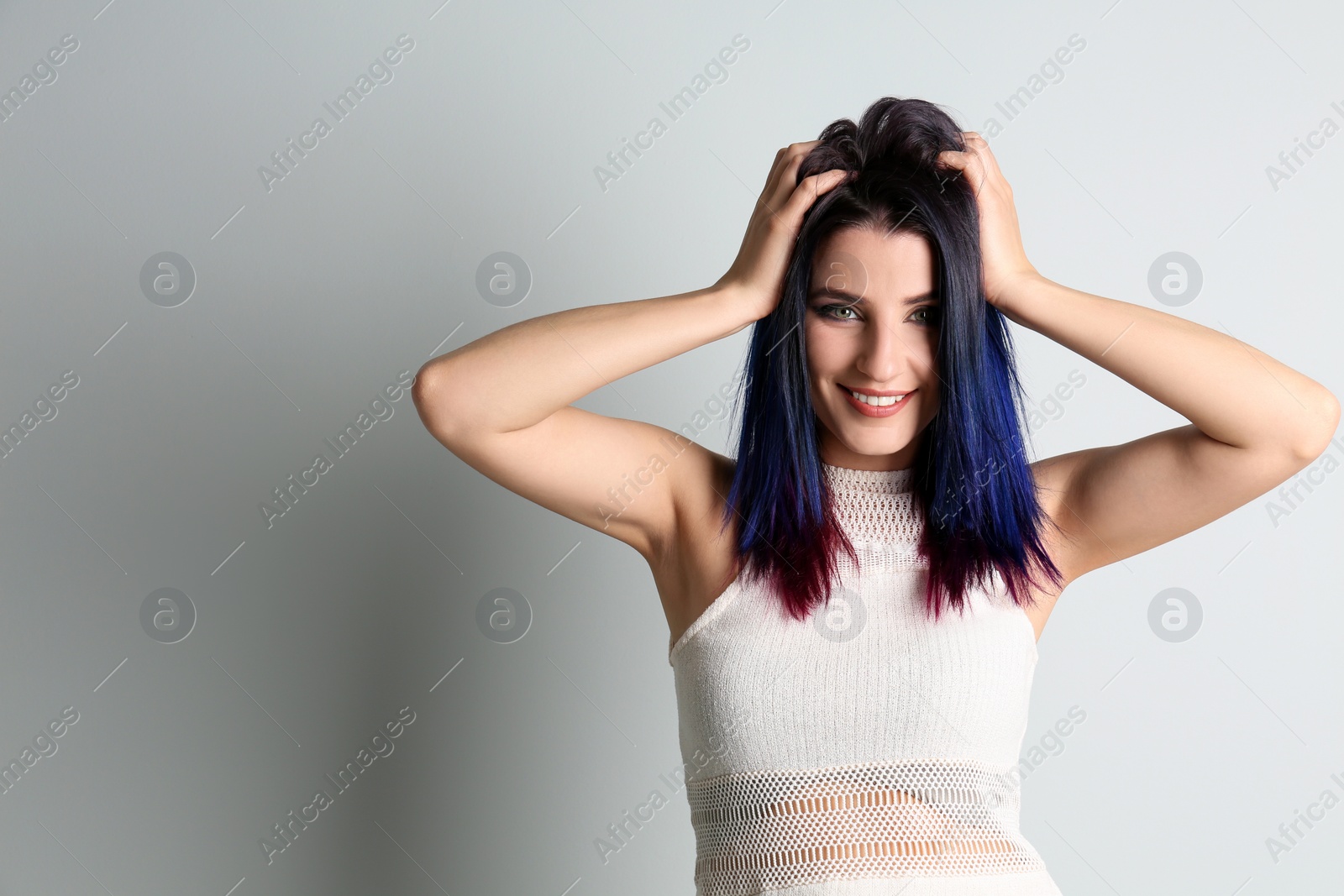 Photo of Young woman with bright dyed hair on light background, space for text