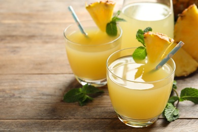 Delicious fresh pineapple juice with mint on wooden table, closeup. Space for text