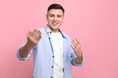 Photo of Handsome man inviting to come in against pink background
