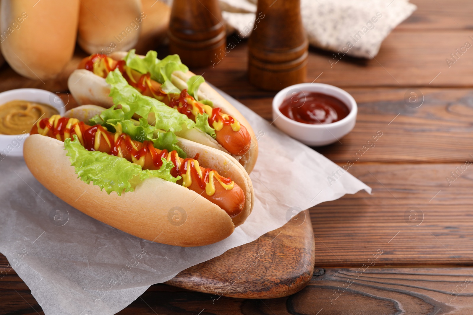 Photo of Tasty hot dogs with lettuce, ketchup and mustard on wooden table. Space for text