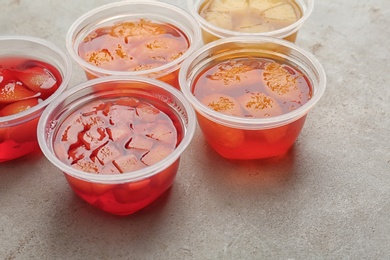 Photo of Plastic containers with tasty jelly desserts on grey table