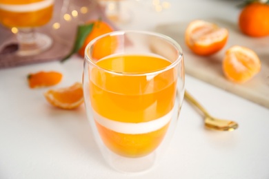 Photo of Delicious tangerine jelly in glass on white table, closeup