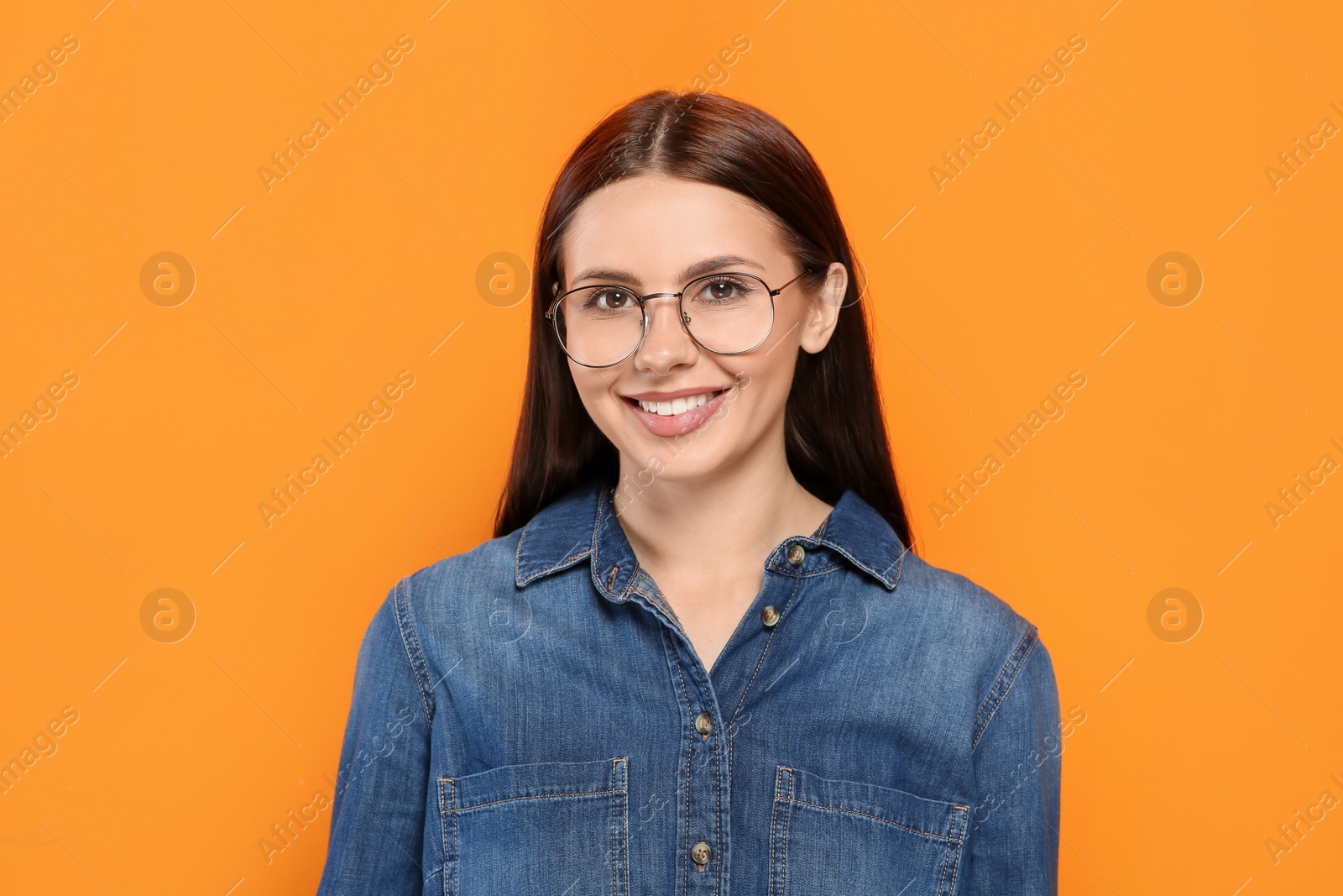 Photo of Portrait of smiling woman in stylish eyeglasses on orange background