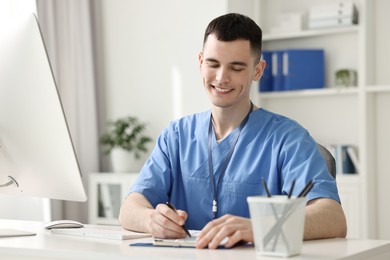 Photo of Smiling medical assistant writing something in office