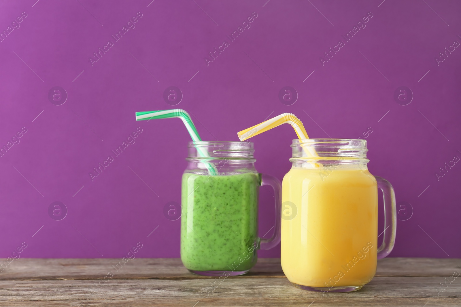 Photo of Mason jars with delicious detox smoothies on table