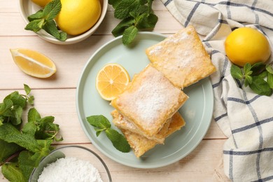 Photo of Tasty lemon bars with powdered sugar and mint on wooden table, flat lay