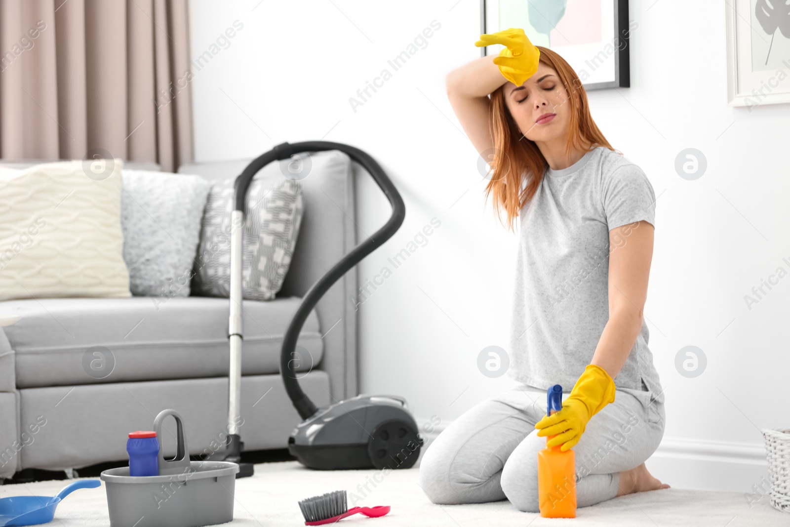 Photo of Tired housewife cleaning carpet at home