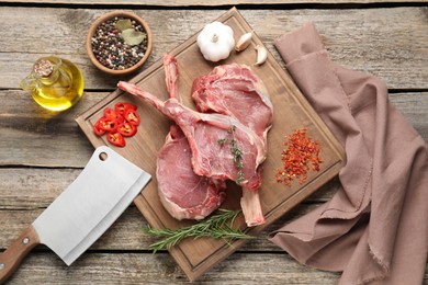 Photo of Fresh tomahawk beef cuts, butcher knife and spices on wooden table, top view