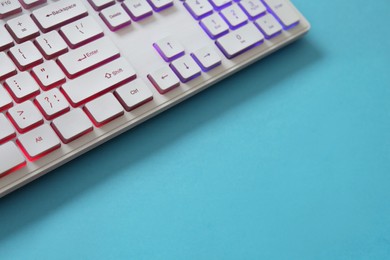 Photo of Modern RGB keyboard on turquoise background, closeup. Space for text