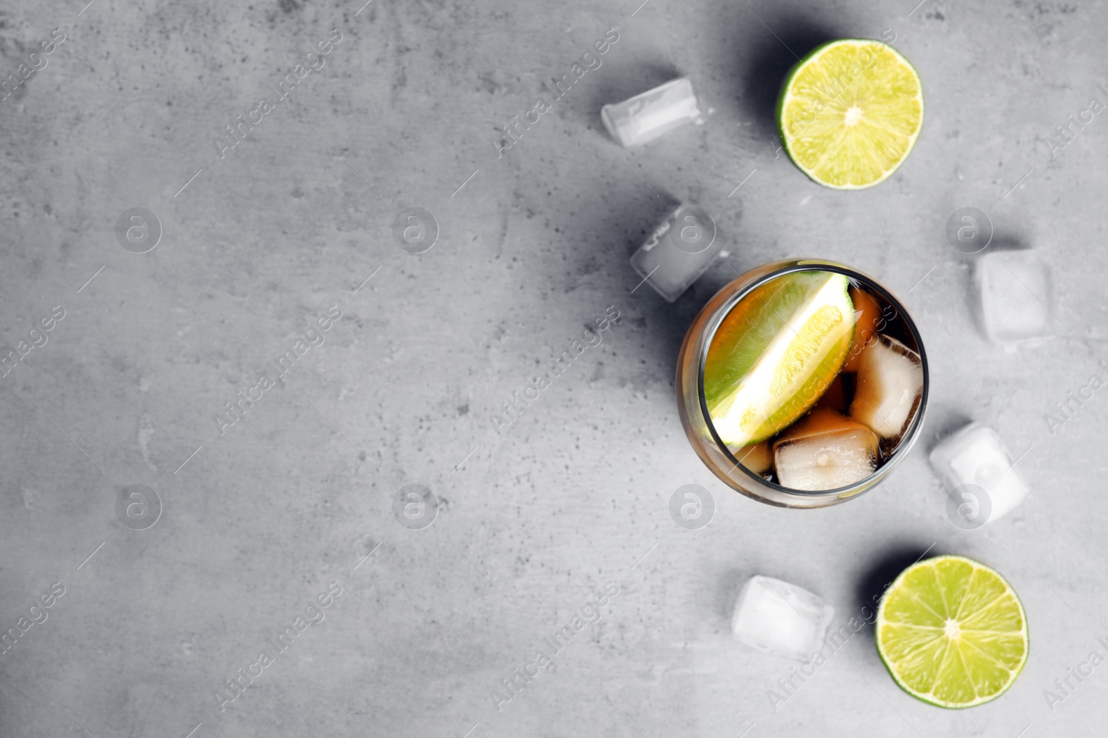 Photo of Flat lay composition with refreshing soda drink, ice cubes and limes on grey table, space for text