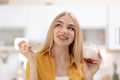 Photo of Young woman with yogurt on blurred background