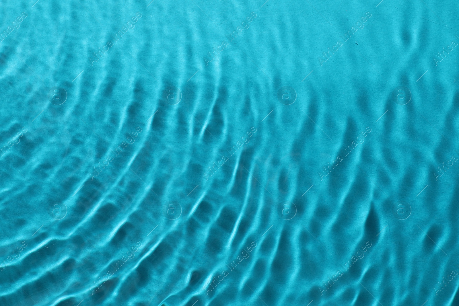 Photo of Rippled surface of clear water on light blue background, top view