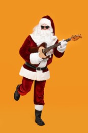 Photo of Santa Claus playing electric guitar on yellow background. Christmas music