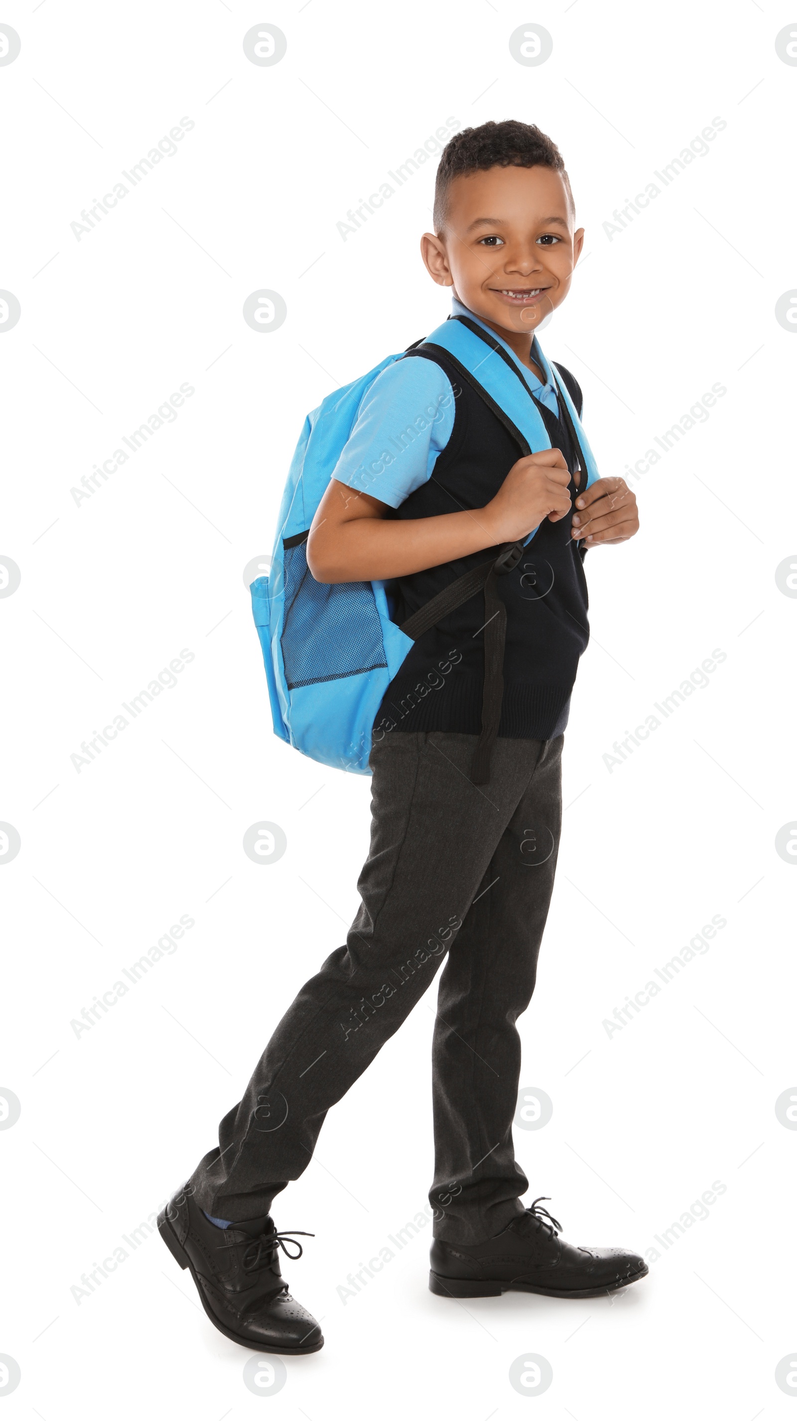 Photo of Full length portrait of cute African-American boy in school uniform with backpack on white background